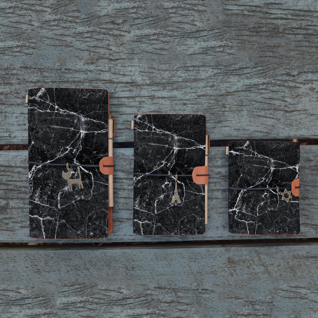 
three sizes of midori style traveler's notebook with moody marble design on the wooden bench