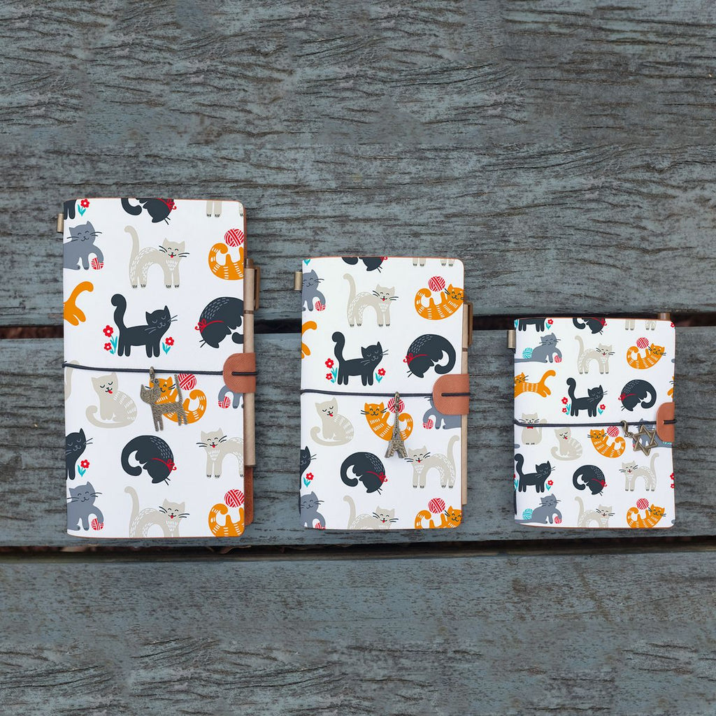
three sizes of midori style traveler's notebook with playful pussycats design on the wooden bench