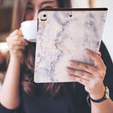 a girl is holding and viewing personalized iPad folio case with Marble design 