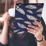 a girl is holding and viewing personalized iPad folio case with Feather design 